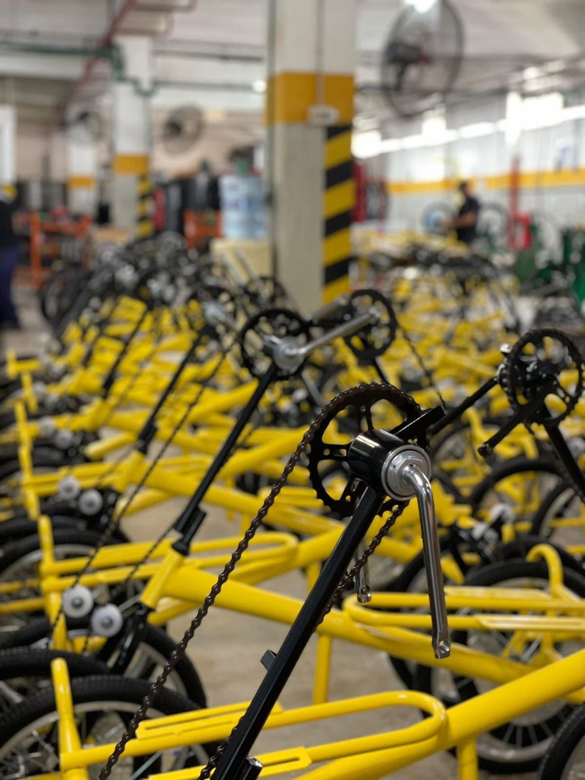 Interior del taller de producción con múltiples estructuras y cuadros de bicicletas amarillas alineados