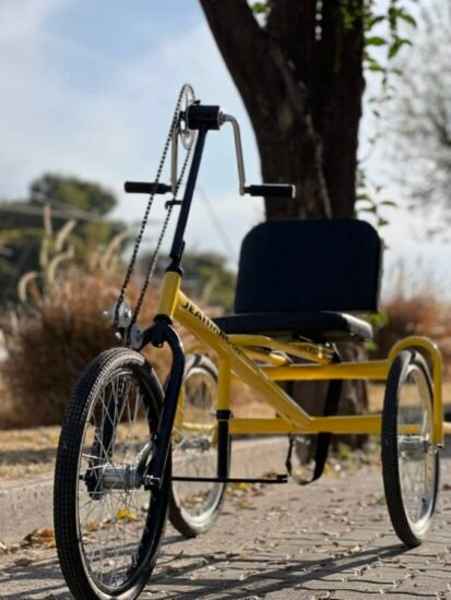 Bicicleta adaptada de tres ruedas de color amarillo estacionada al aire libre