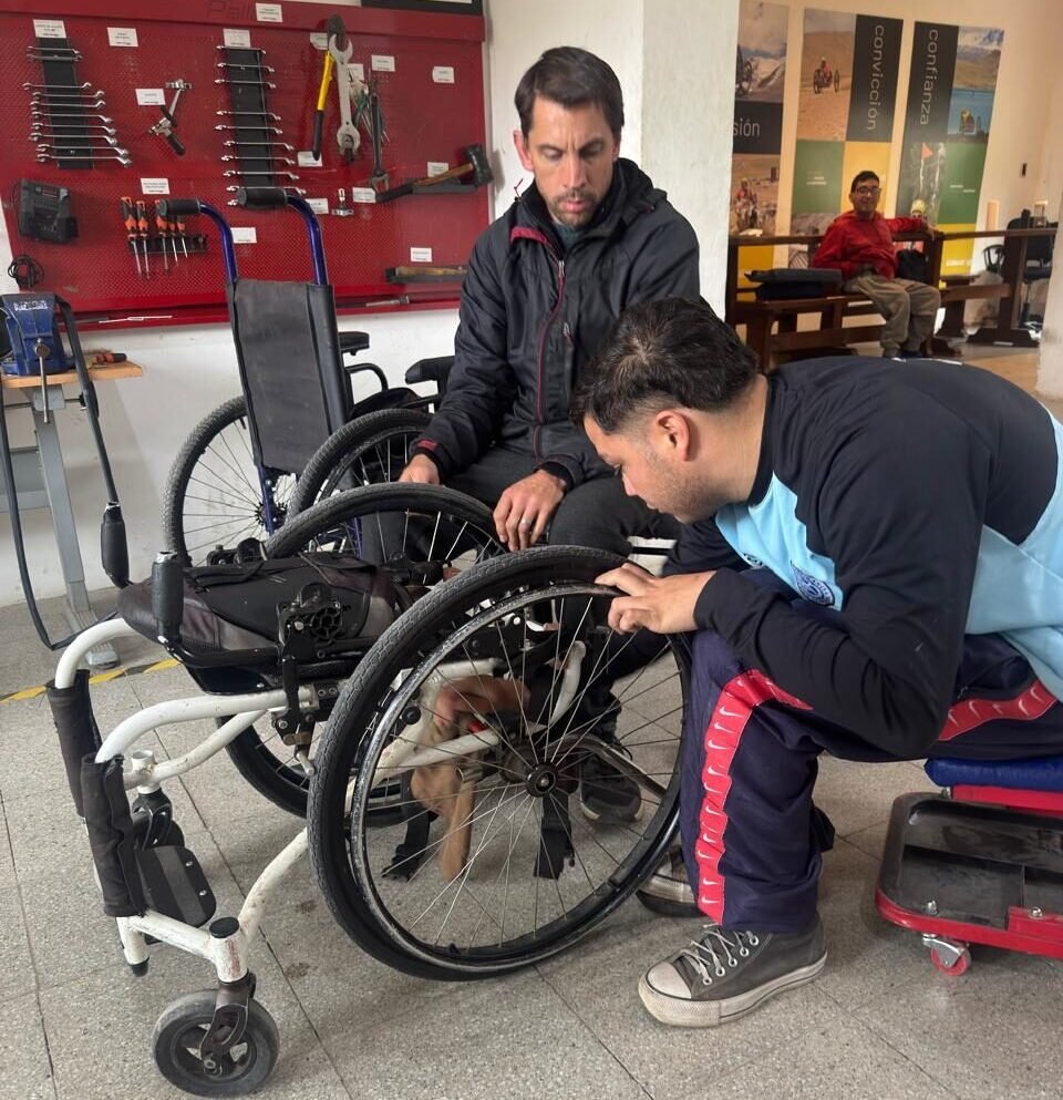 Dos técnicos trabajando en el mantenimiento y revisión de una silla de ruedas en el taller